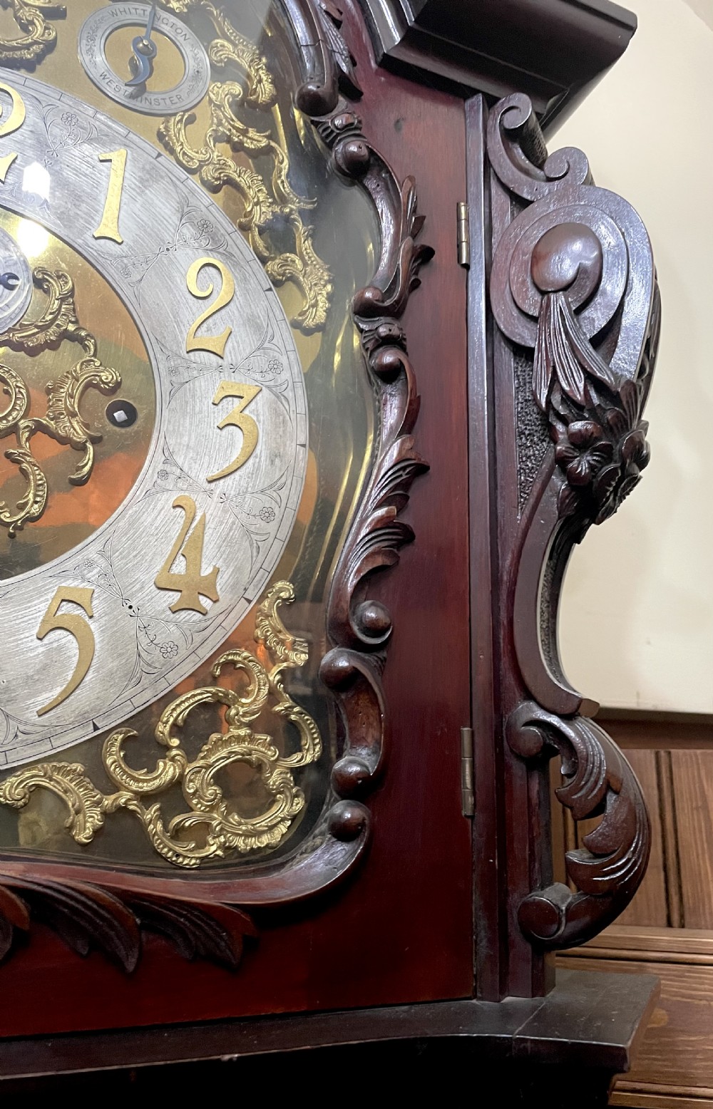 An antique Chippendale Revival mahogany longcase clock featuring a carved swan-neck pediment, floral marquetry, and a brass dial behind a glazed door. View IV