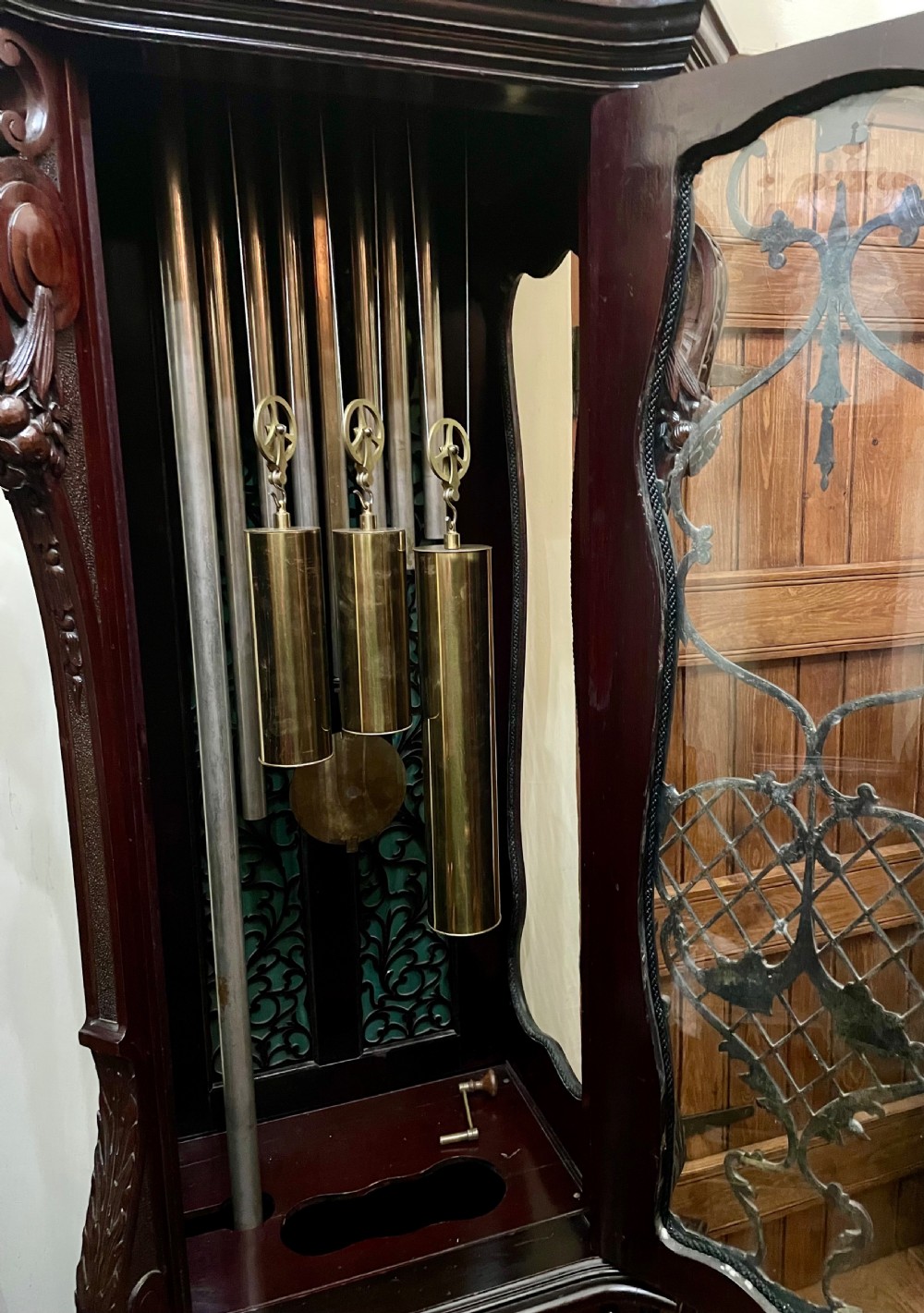 An antique Chippendale Revival mahogany longcase clock featuring a carved swan-neck pediment, floral marquetry, and a brass dial behind a glazed door. View XII