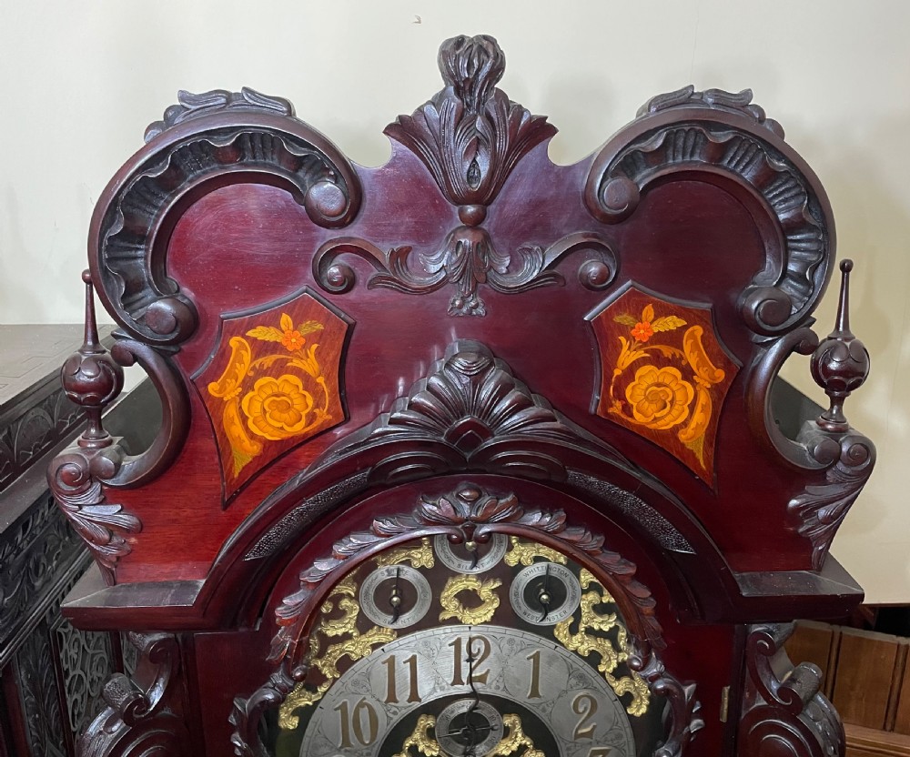 An antique Chippendale Revival mahogany longcase clock featuring a carved swan-neck pediment, floral marquetry, and a brass dial behind a glazed door. View XV