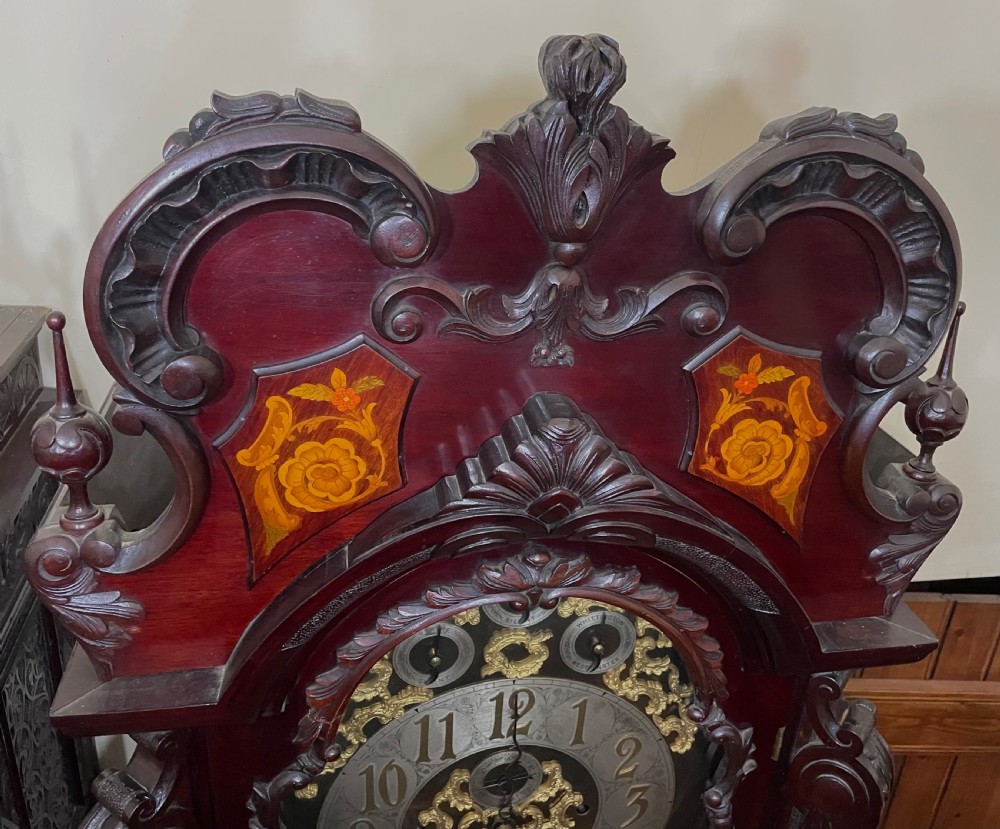 An antique Chippendale Revival mahogany longcase clock featuring a carved swan-neck pediment, floral marquetry, and a brass dial behind a glazed door. View XVII