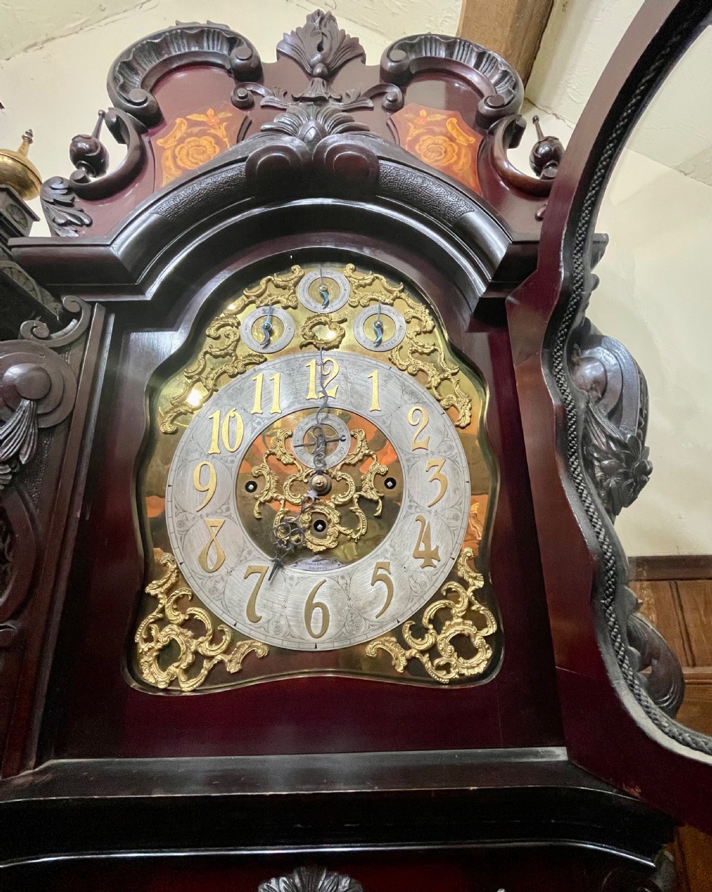 An antique Chippendale Revival mahogany longcase clock featuring a carved swan-neck pediment, floral marquetry, and a brass dial behind a glazed door. View XX