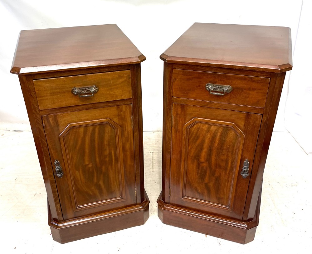 A pair of Victorian mahogany bedside cabinets featuring top drawers, panelled cupboard doors with metal handles, and solid plinth bases. View II