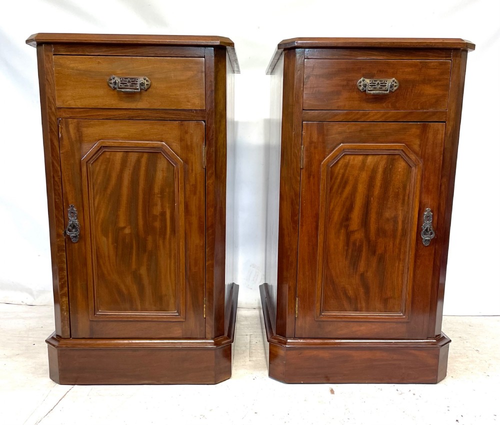 A pair of Victorian mahogany bedside cabinets featuring top drawers, panelled cupboard doors with metal handles, and solid plinth bases. View III