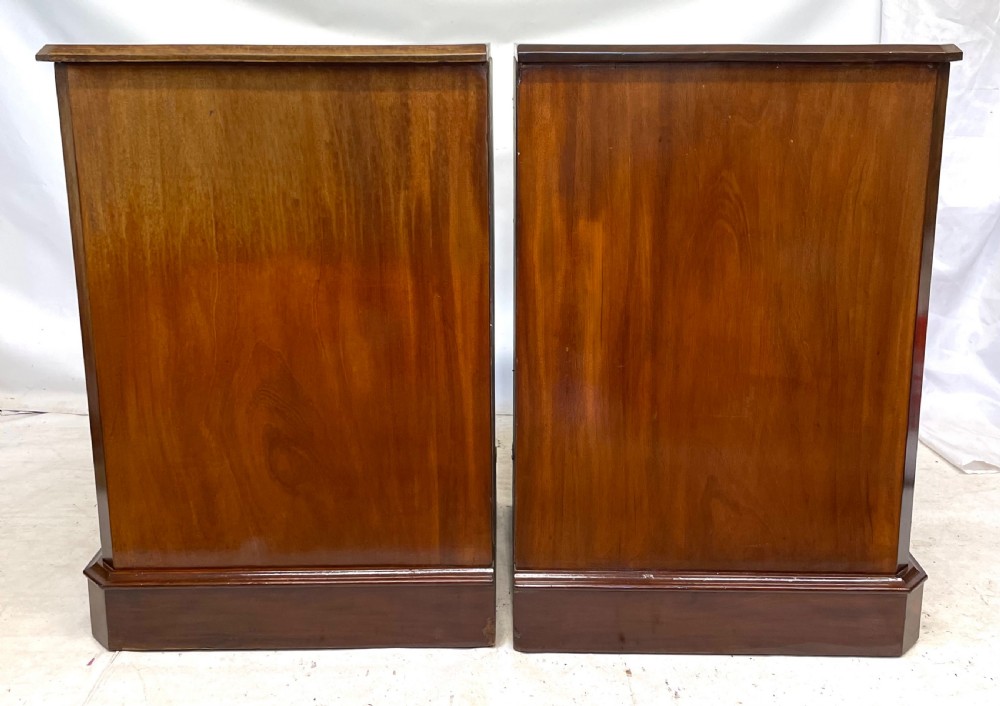A pair of Victorian mahogany bedside cabinets featuring top drawers, panelled cupboard doors with metal handles, and solid plinth bases. View XII