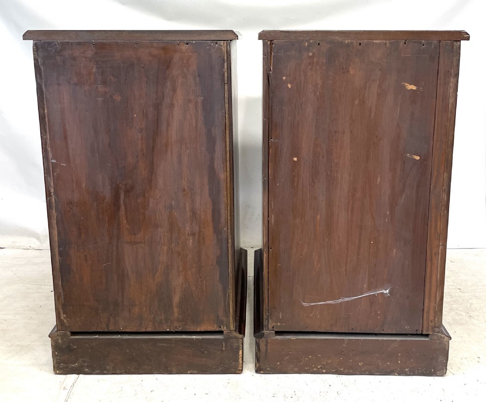 A pair of Victorian mahogany bedside cabinets featuring top drawers, panelled cupboard doors with metal handles, and solid plinth bases. View XVI