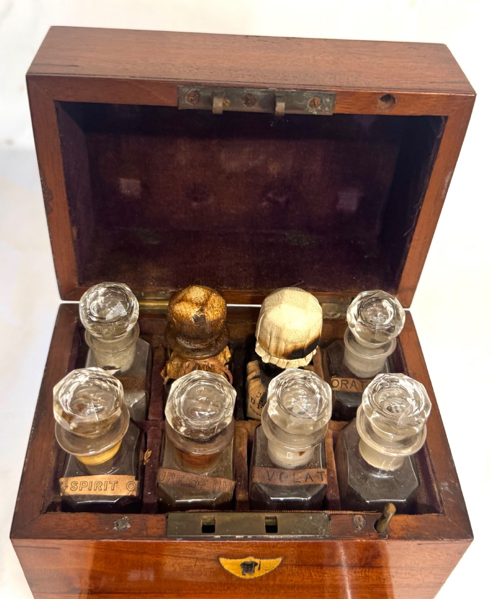 An antique wooden apothecary box shown open with glass stoppered bottles in top compartments and labelled vials in a velvet-lined lower drawer. View III