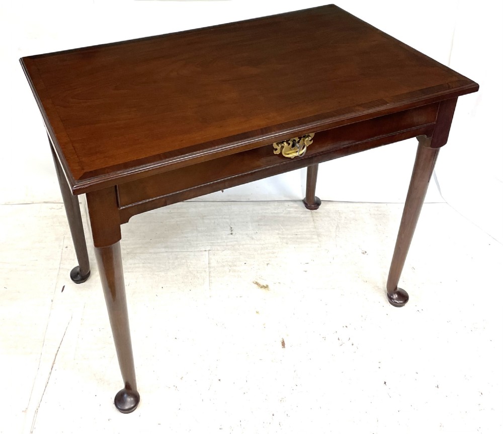An antique Georgian mahogany side table featuring a rectangular top with a moulded rim, a single drawer with brass hardware, and slender cabriole legs ending in pad feet.