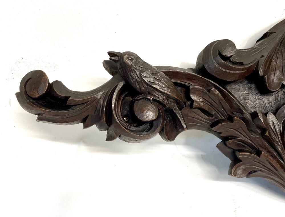 A horizontally orientated Victorian carved oak aneroid barometer featuring a central circular brass dial flanked by carved leaf motifs and bird figures. View III