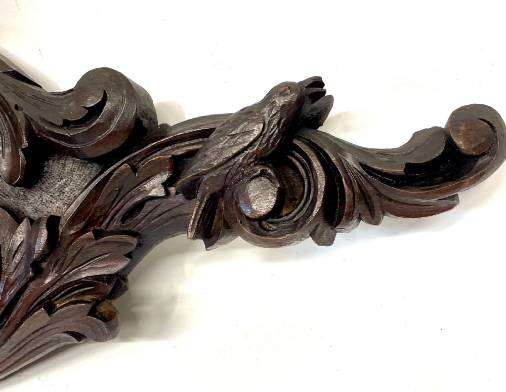 A horizontally orientated Victorian carved oak aneroid barometer featuring a central circular brass dial flanked by carved leaf motifs and bird figures. View V