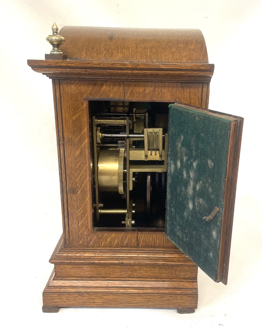 A carved oak bracket clock featuring an arched pediment, brass corner finials, side fretwork panels, and a brass dial with silvered chapter ring. View XI