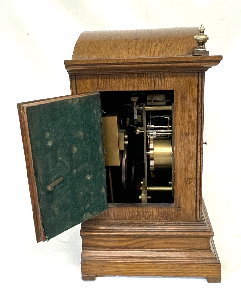 A carved oak bracket clock featuring an arched pediment, brass corner finials, side fretwork panels, and a brass dial with silvered chapter ring. View XII