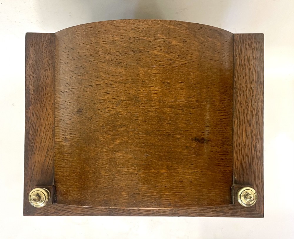 A carved oak bracket clock featuring an arched pediment, brass corner finials, side fretwork panels, and a brass dial with silvered chapter ring. View XVI