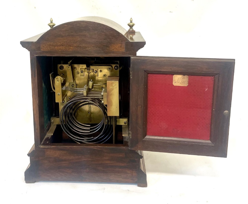 A carved oak bracket clock featuring an arched pediment, brass corner finials, side fretwork panels, and a brass dial with silvered chapter ring. View XVIII