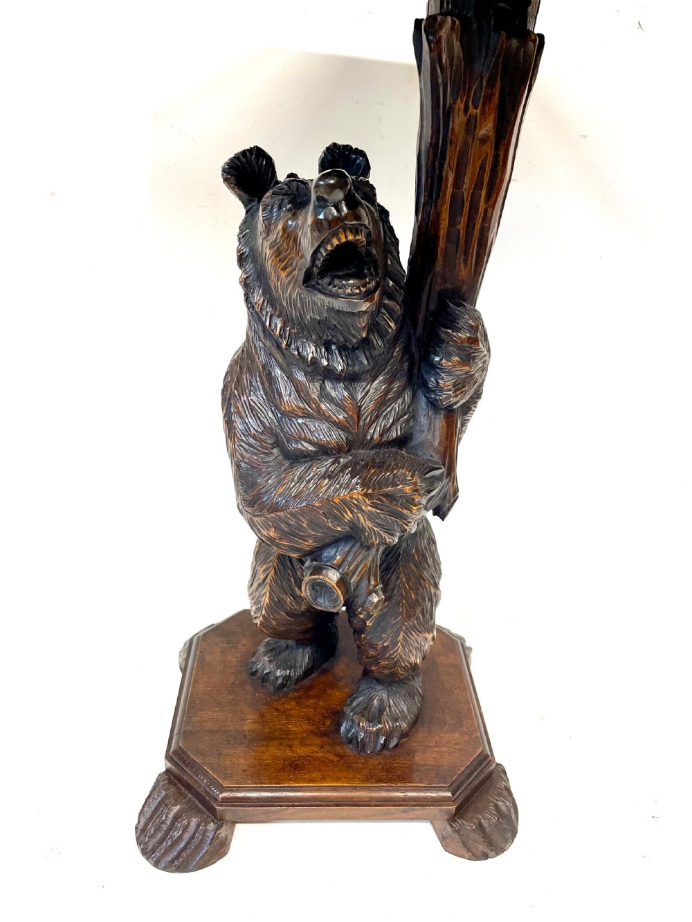 A dark wood side table with an octagonal top deeply carved with floral details, supported by a central tree trunk and a carved standing bear figure. View IV