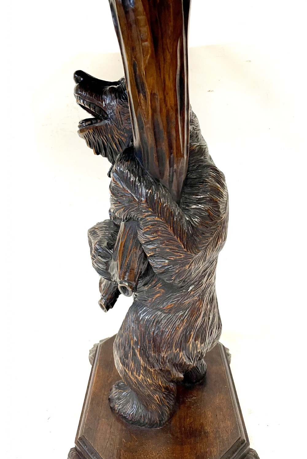 A dark wood side table with an octagonal top deeply carved with floral details, supported by a central tree trunk and a carved standing bear figure. View VII