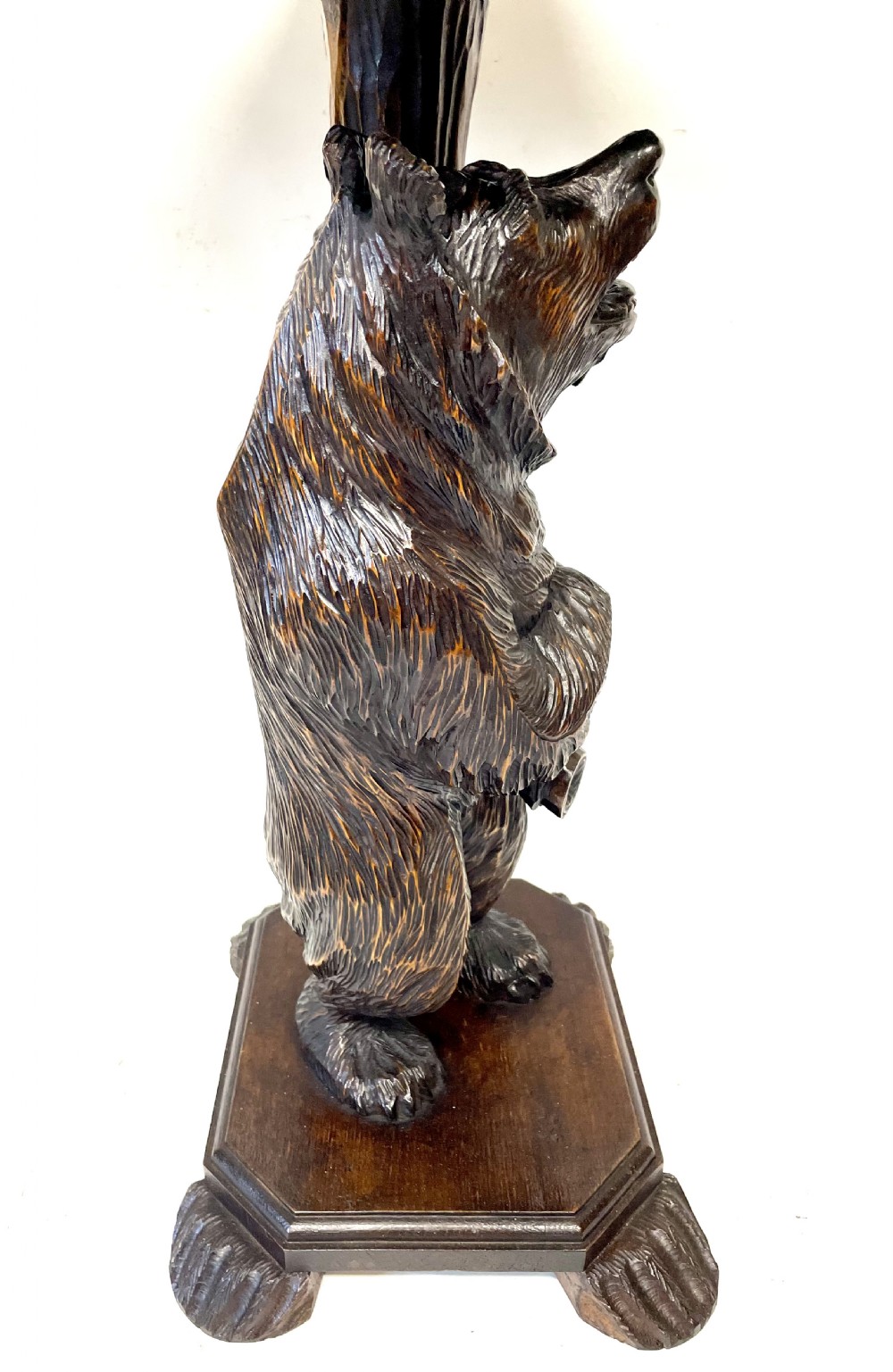 A dark wood side table with an octagonal top deeply carved with floral details, supported by a central tree trunk and a carved standing bear figure. View IX