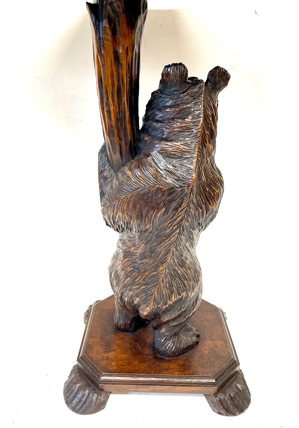 A dark wood side table with an octagonal top deeply carved with floral details, supported by a central tree trunk and a carved standing bear figure. View XII