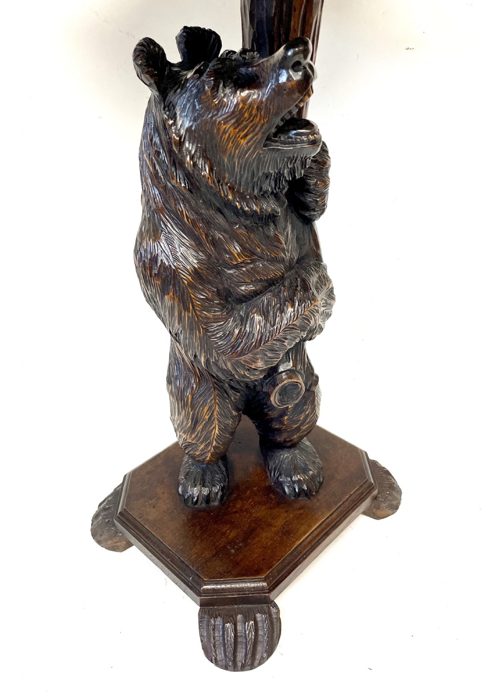 A dark wood side table with an octagonal top deeply carved with floral details, supported by a central tree trunk and a carved standing bear figure. View XVI