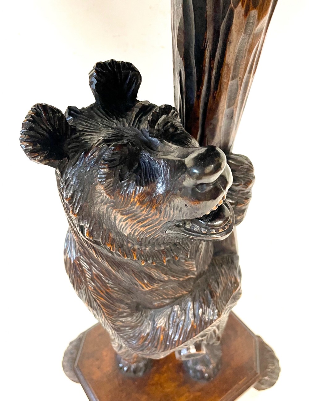 A dark wood side table with an octagonal top deeply carved with floral details, supported by a central tree trunk and a carved standing bear figure. View XVII
