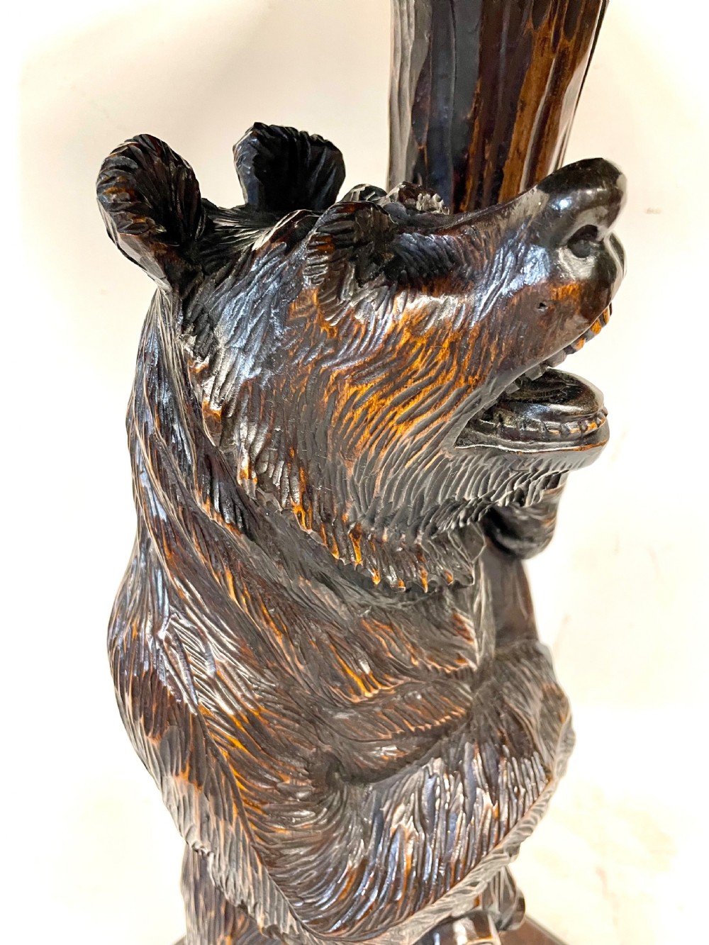 A dark wood side table with an octagonal top deeply carved with floral details, supported by a central tree trunk and a carved standing bear figure. View XVIII