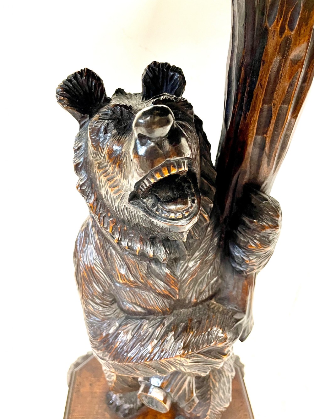 A dark wood side table with an octagonal top deeply carved with floral details, supported by a central tree trunk and a carved standing bear figure. View XIX