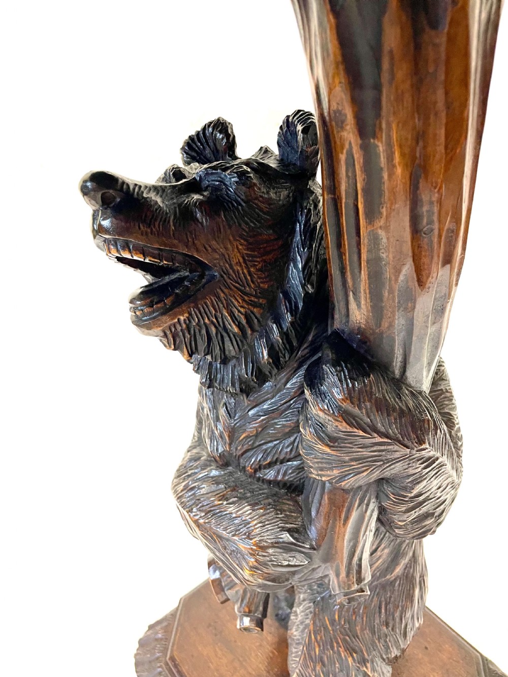 A dark wood side table with an octagonal top deeply carved with floral details, supported by a central tree trunk and a carved standing bear figure. View XXI