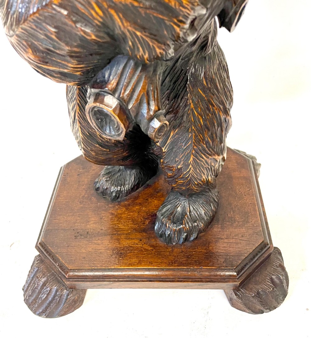 A dark wood side table with an octagonal top deeply carved with floral details, supported by a central tree trunk and a carved standing bear figure. View XXII