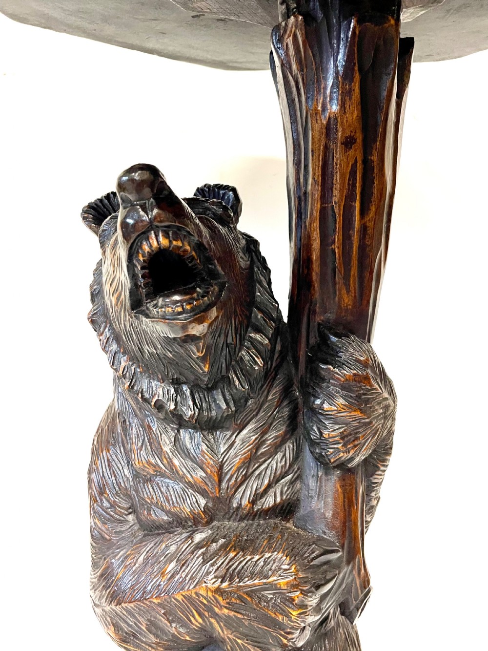 A dark wood side table with an octagonal top deeply carved with floral details, supported by a central tree trunk and a carved standing bear figure. View XXIII