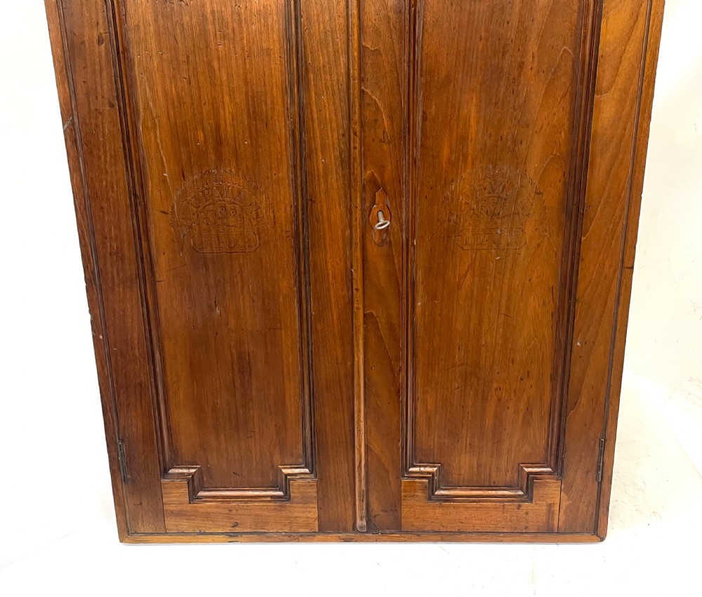 An antique cedar wood wall cabinet featuring two panelled doors with faint engraved H. Upmann Habana cigar branding and a central keyhole. View III