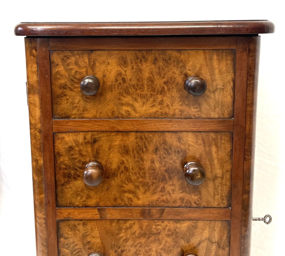 A pair of narrow Victorian burr walnut bedside cabinets featuring four drawers each, turned wooden handles, side locking mechanisms, and plinth bases. View X