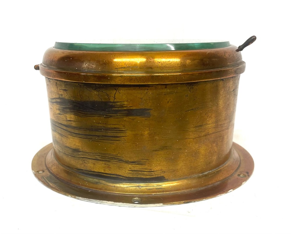 A circular brass-cased ship clock with a white dial displaying black Roman numerals, spade hands, and the maker name Prescot Clock Co. View X
