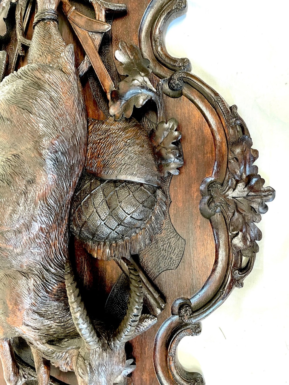 A pair of 19th-century carved dark wood wall plaques depicting hunted game, including a chamois and birds framed by oak foliage and hunting gear. View VIII