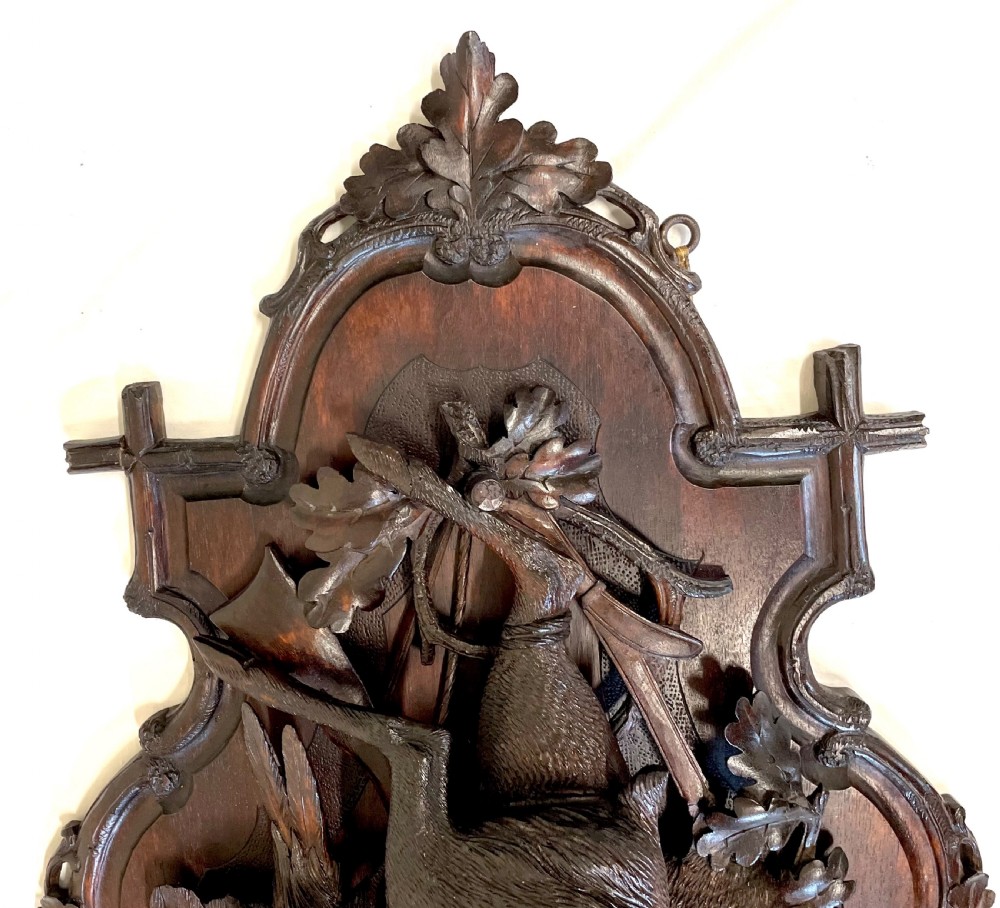 A pair of 19th-century carved dark wood wall plaques depicting hunted game, including a chamois and birds framed by oak foliage and hunting gear. View IX