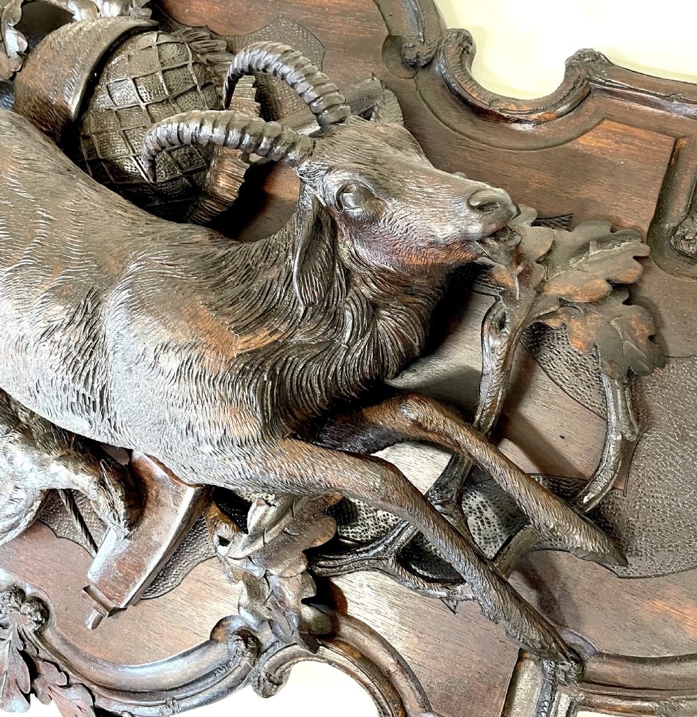 A pair of 19th-century carved dark wood wall plaques depicting hunted game, including a chamois and birds framed by oak foliage and hunting gear. View XII