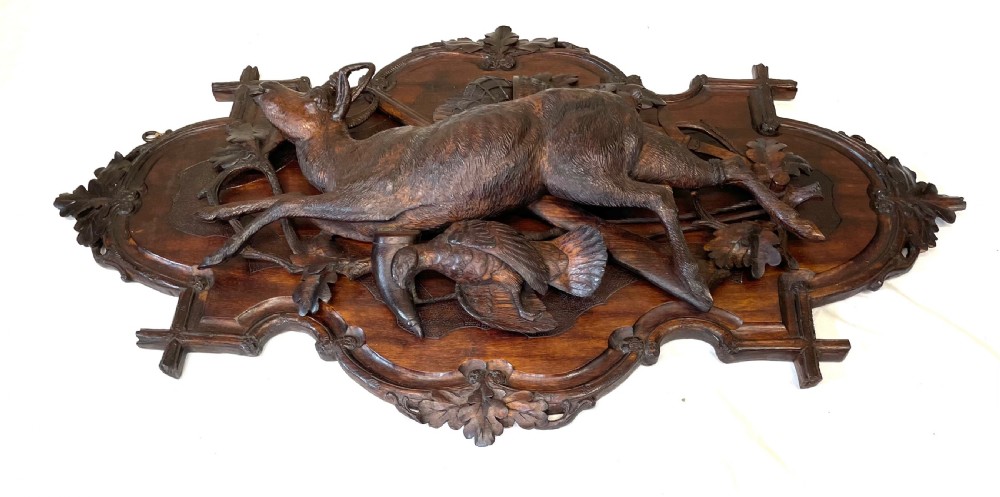 A pair of 19th-century carved dark wood wall plaques depicting hunted game, including a chamois and birds framed by oak foliage and hunting gear. View XIV