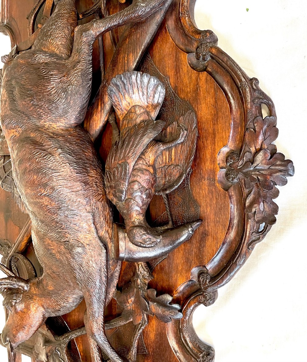 A pair of 19th-century carved dark wood wall plaques depicting hunted game, including a chamois and birds framed by oak foliage and hunting gear. View XV