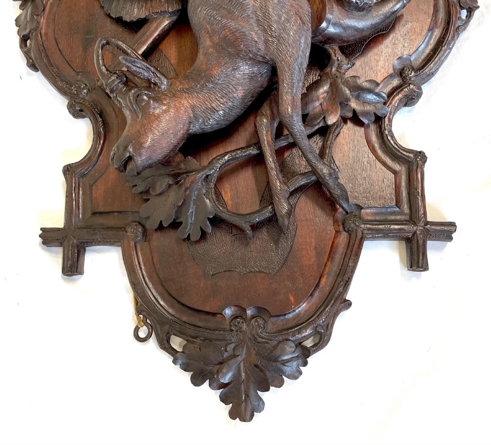 A pair of 19th-century carved dark wood wall plaques depicting hunted game, including a chamois and birds framed by oak foliage and hunting gear. View XVI