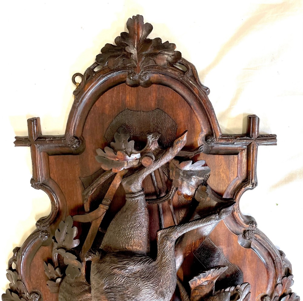 A pair of 19th-century carved dark wood wall plaques depicting hunted game, including a chamois and birds framed by oak foliage and hunting gear. View XVII