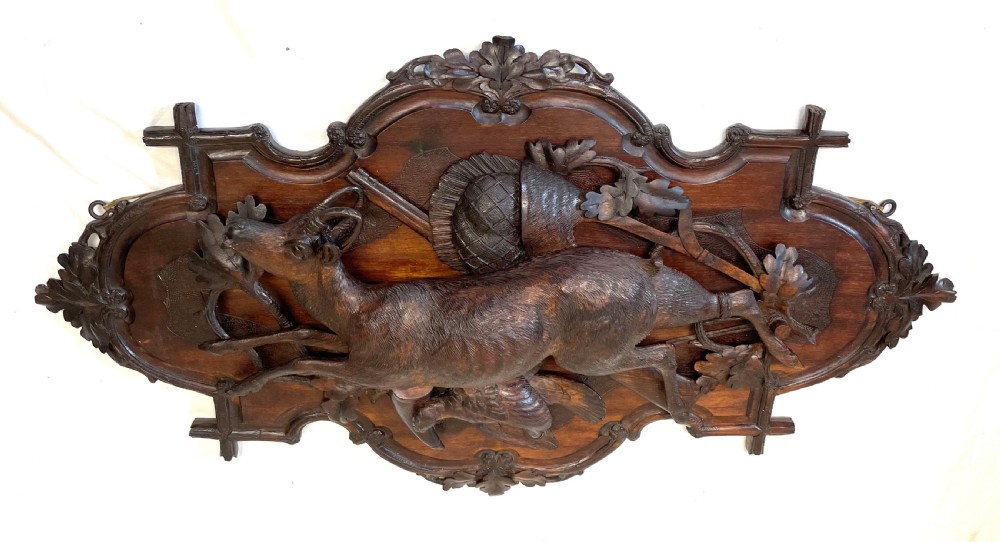 A pair of 19th-century carved dark wood wall plaques depicting hunted game, including a chamois and birds framed by oak foliage and hunting gear. View XVIII