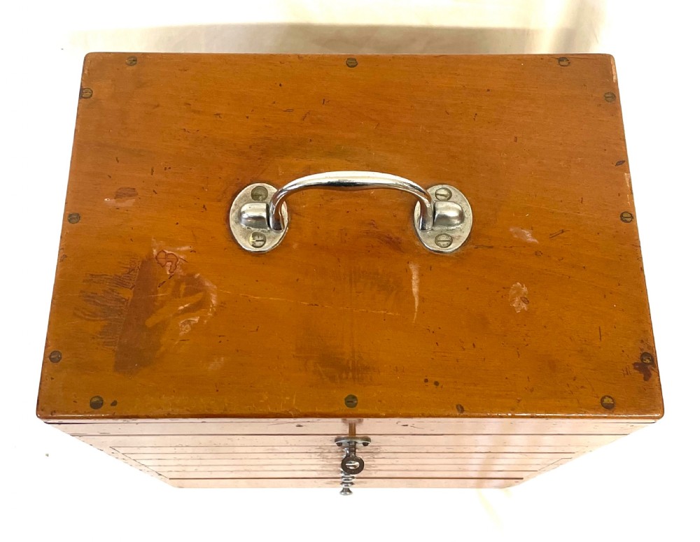 A rectangular wooden portable dental cabinet with six graduated drawers, silver-coloured metal pull knobs, a metal keyhole escutcheon, and a top carrying handle. View IX
