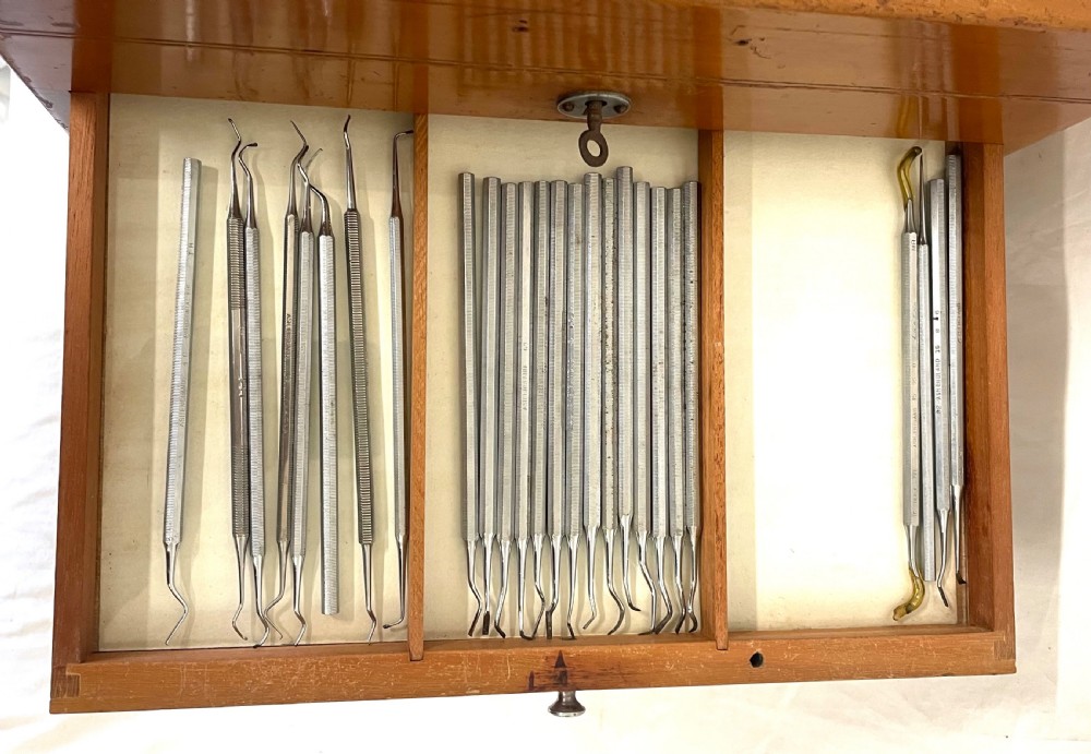 A rectangular wooden portable dental cabinet with six graduated drawers, silver-coloured metal pull knobs, a metal keyhole escutcheon, and a top carrying handle. View XIII