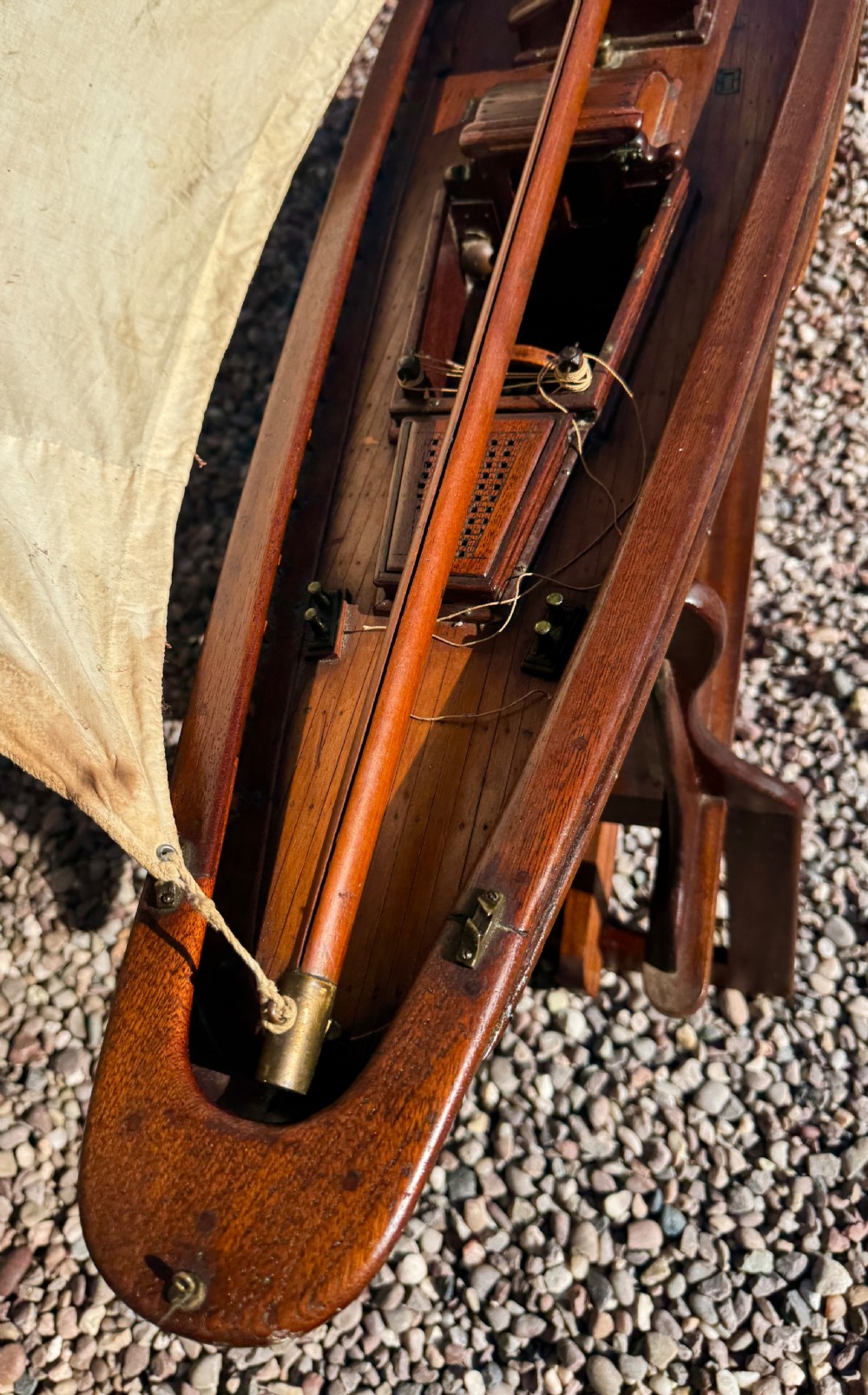 A large Victorian wooden pond yacht with stitched fabric sails, brass deck fittings, and a carved wooden keel, displayed on a wooden stand. View XIII