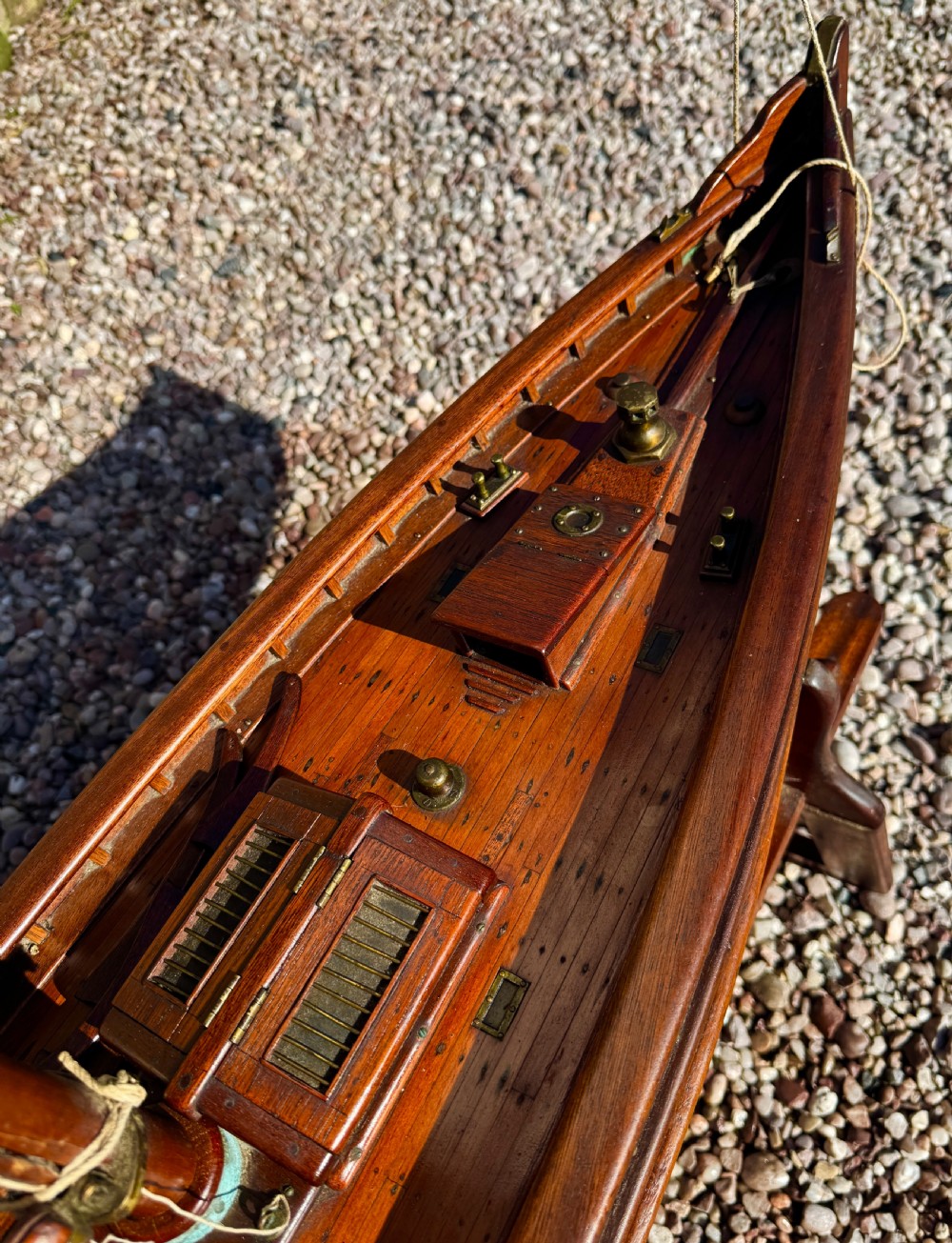 A large Victorian wooden pond yacht with stitched fabric sails, brass deck fittings, and a carved wooden keel, displayed on a wooden stand. View XV