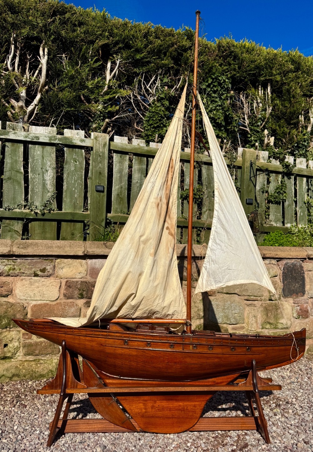 A large Victorian wooden pond yacht with stitched fabric sails, brass deck fittings, and a carved wooden keel, displayed on a wooden stand. View XIX