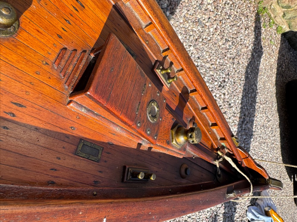 A large Victorian wooden pond yacht with stitched fabric sails, brass deck fittings, and a carved wooden keel, displayed on a wooden stand. View XXIV