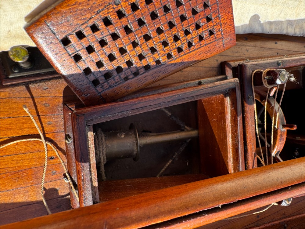 A large Victorian wooden pond yacht with stitched fabric sails, brass deck fittings, and a carved wooden keel, displayed on a wooden stand. View XXV