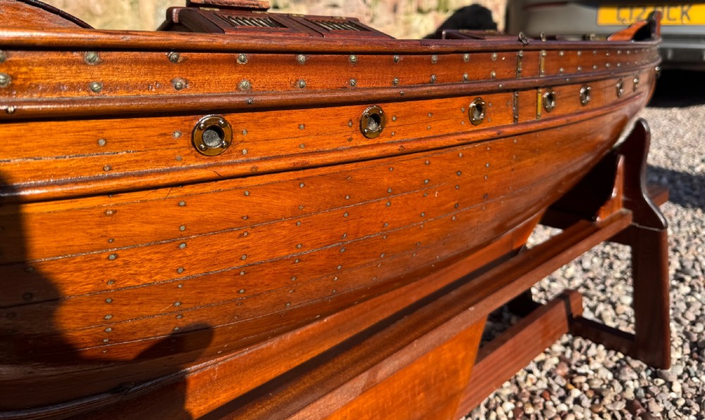 A large Victorian wooden pond yacht with stitched fabric sails, brass deck fittings, and a carved wooden keel, displayed on a wooden stand. View XXVIII