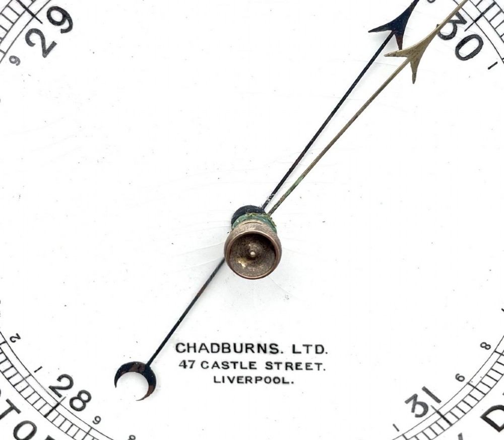 An antique dark carved oak banjo aneroid barometer featuring an upper thermometer tube and a circular brass-rimmed lower dial set into a wooden case. View XIII