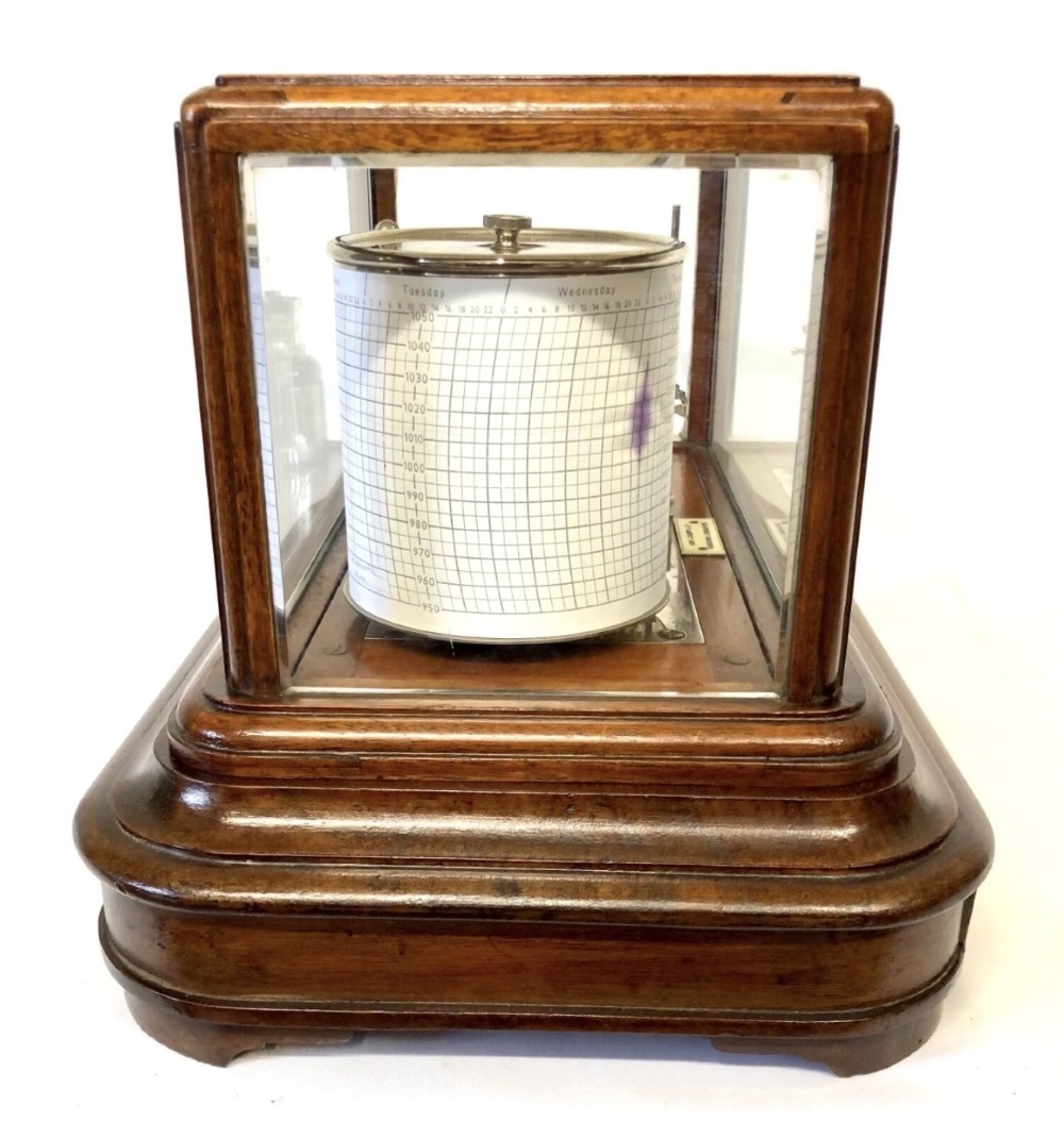 An antique mahogany and glass-cased recording barograph showing internal mechanical brass drums, aneroid pressure cells, and an integrated thermometer above a base drawer. View VII