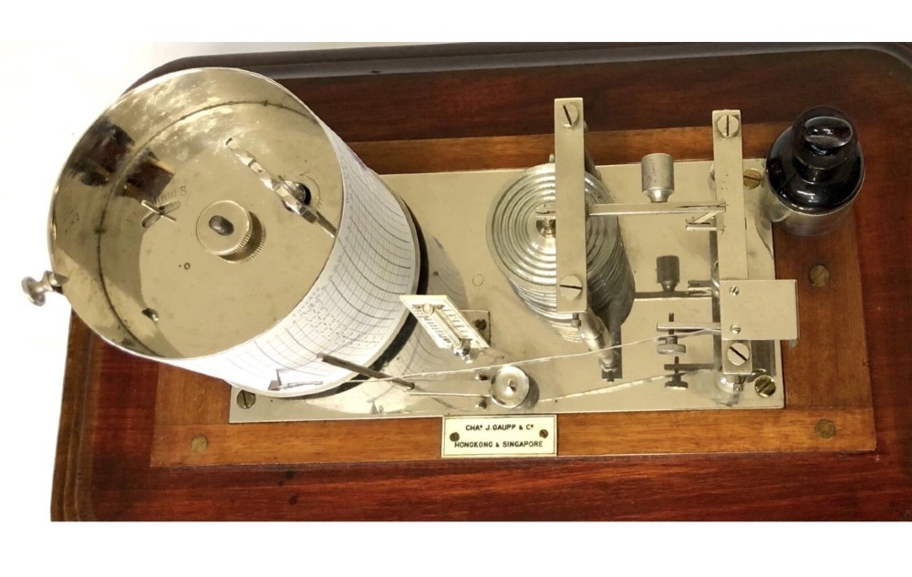 An antique mahogany and glass-cased recording barograph showing internal mechanical brass drums, aneroid pressure cells, and an integrated thermometer above a base drawer. View X